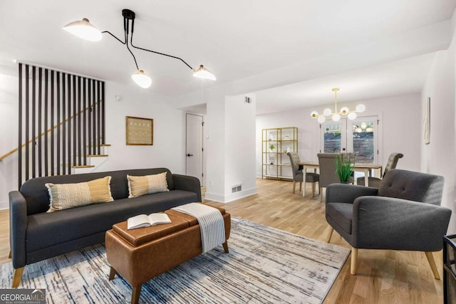 living area featuring baseboards, stairway, visible vents, and light wood-style floors