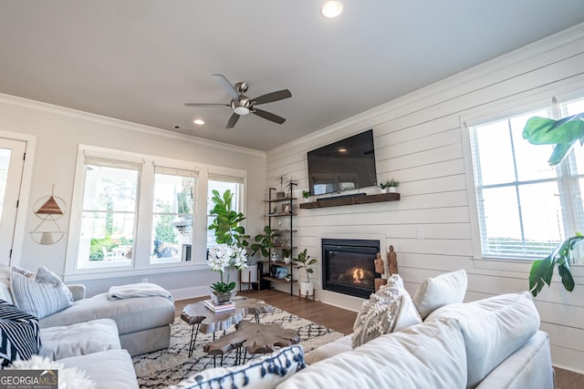 living room featuring ornamental molding, plenty of natural light, and a glass covered fireplace