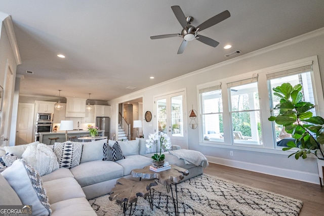 living area with stairs, visible vents, crown molding, and wood finished floors