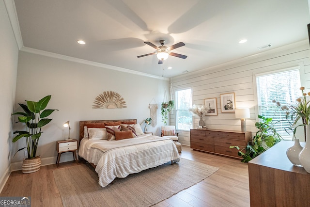 bedroom featuring light wood-style floors, baseboards, visible vents, and ornamental molding