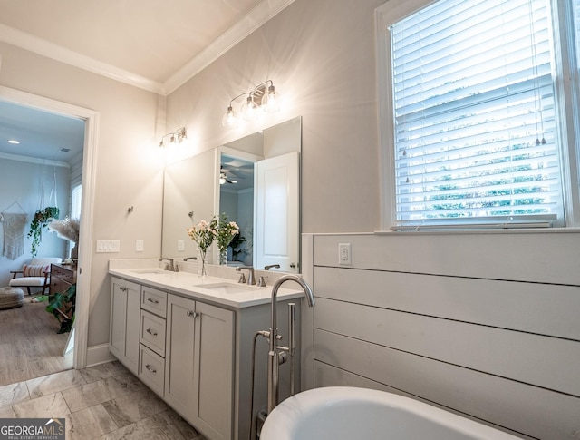 full bath with double vanity, marble finish floor, ornamental molding, and a sink