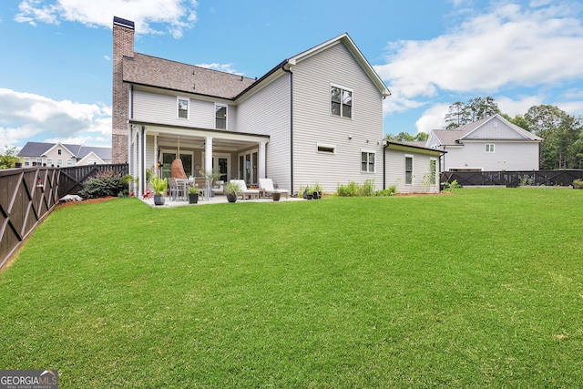 back of house featuring a patio, a yard, a chimney, and a fenced backyard