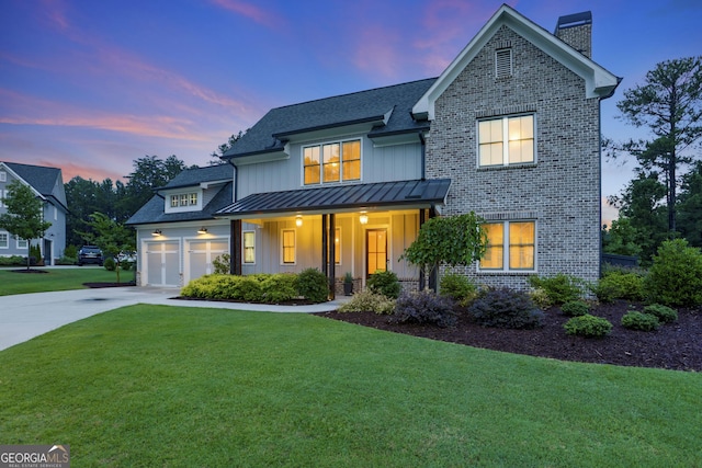 view of front of home with driveway, a garage, a standing seam roof, a front lawn, and brick siding