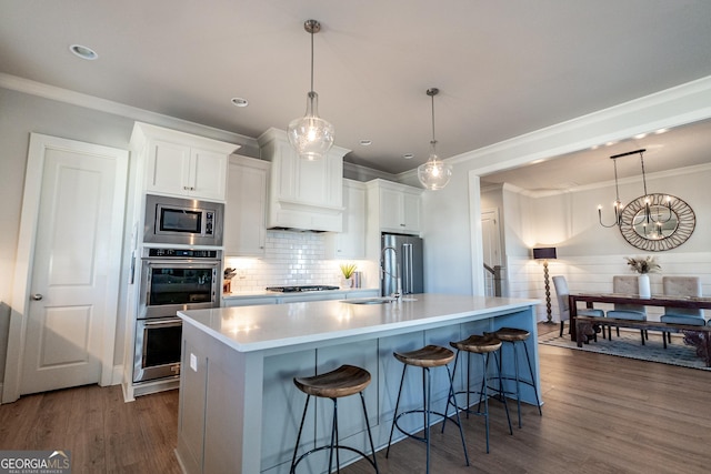 kitchen featuring dark wood-style floors, a center island with sink, appliances with stainless steel finishes, white cabinetry, and a sink