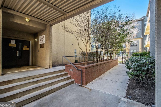 property entrance featuring a gate, fence, and stucco siding