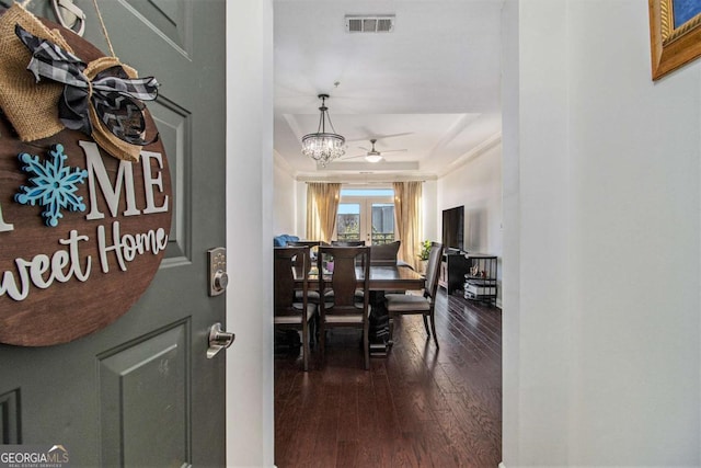 dining space with ceiling fan with notable chandelier, wood finished floors, visible vents, french doors, and a raised ceiling