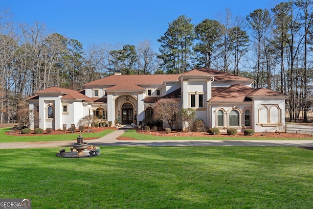 mediterranean / spanish home featuring driveway, a chimney, a front lawn, and stucco siding