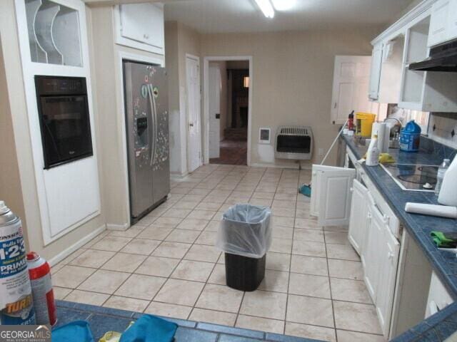 kitchen with heating unit, light tile patterned floors, dark countertops, white cabinetry, and black appliances