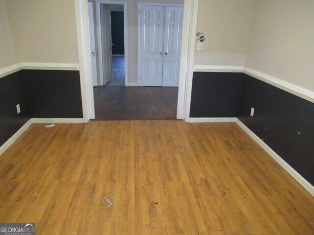 spare room with baseboards and wood finished floors