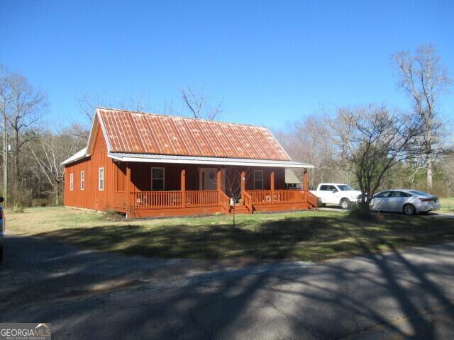 view of front of property with covered porch, metal roof, and a front lawn