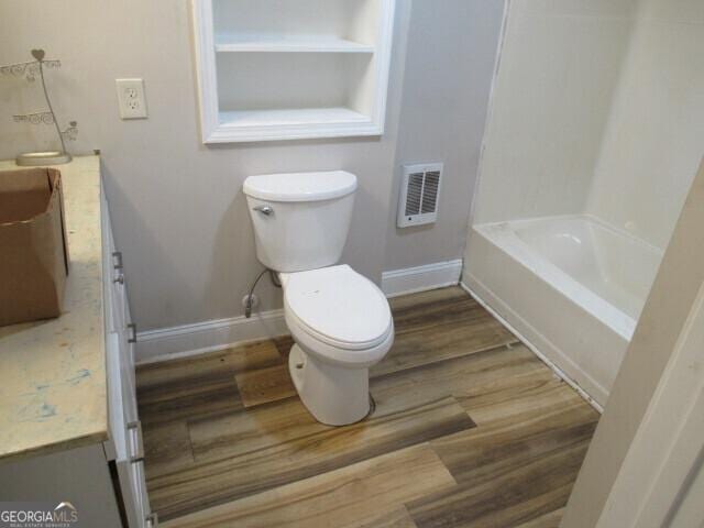 bathroom featuring toilet, vanity, baseboards, and wood finished floors