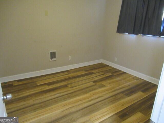 spare room featuring visible vents, baseboards, and wood finished floors