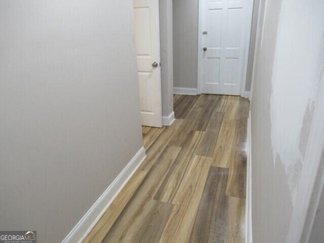 hall featuring wood finished floors and baseboards