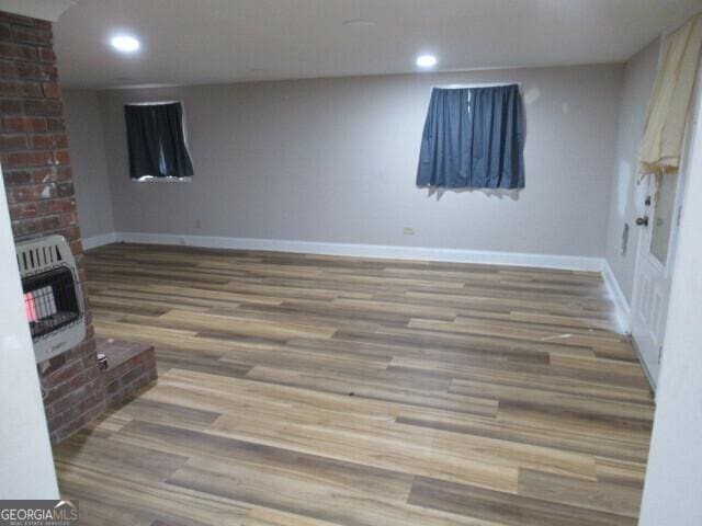 finished below grade area with baseboards, recessed lighting, wood finished floors, and heating unit