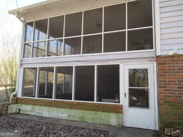 back of house with a sunroom and brick siding