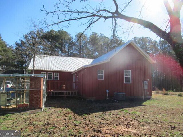 rear view of property with central AC unit and metal roof