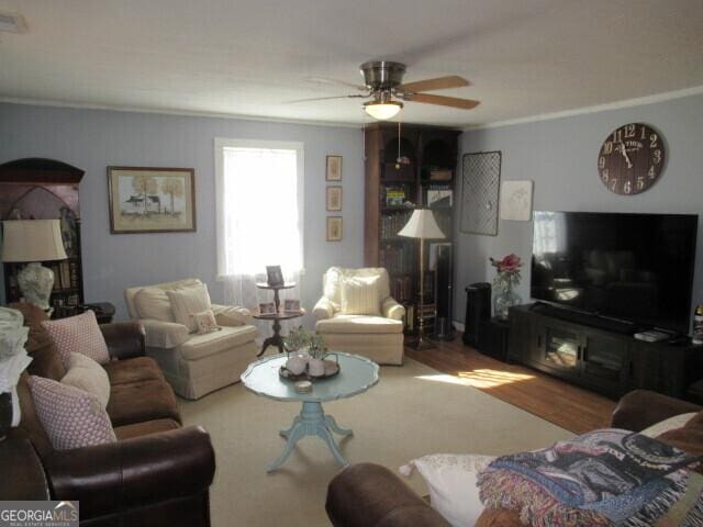 living room with crown molding, ceiling fan, and wood finished floors