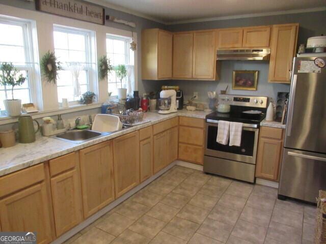 kitchen with light tile patterned floors, light countertops, appliances with stainless steel finishes, a sink, and under cabinet range hood