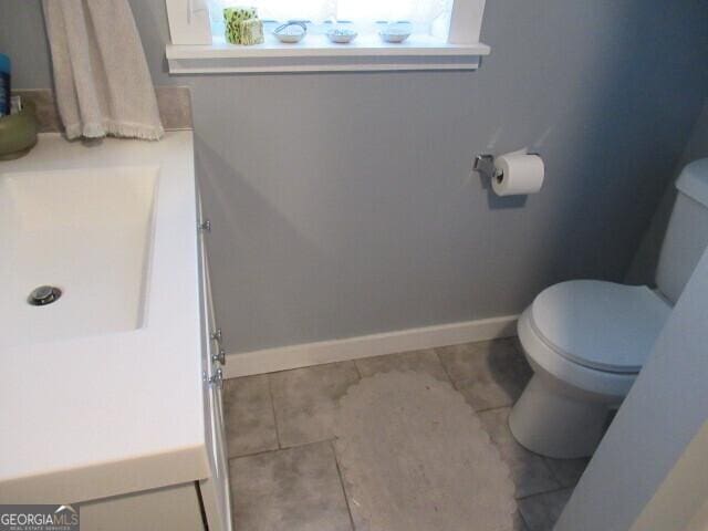 bathroom featuring baseboards, vanity, and toilet