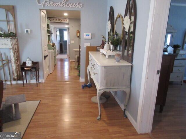 hall featuring light wood-type flooring and baseboards