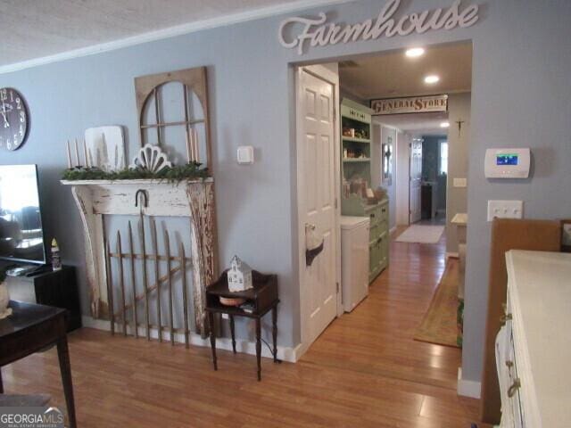 hallway featuring ornamental molding, baseboards, an upstairs landing, and wood finished floors