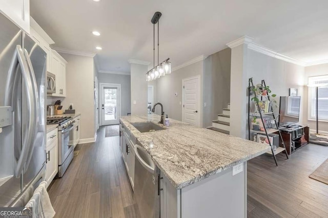 kitchen with dark wood-style floors, appliances with stainless steel finishes, a sink, and a center island with sink