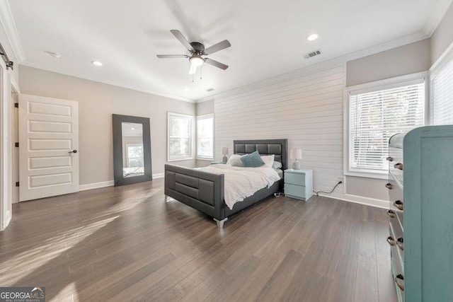 bedroom with dark wood-style floors, visible vents, ornamental molding, and baseboards