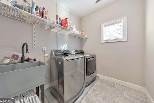 laundry area with a sink, laundry area, washing machine and clothes dryer, and baseboards