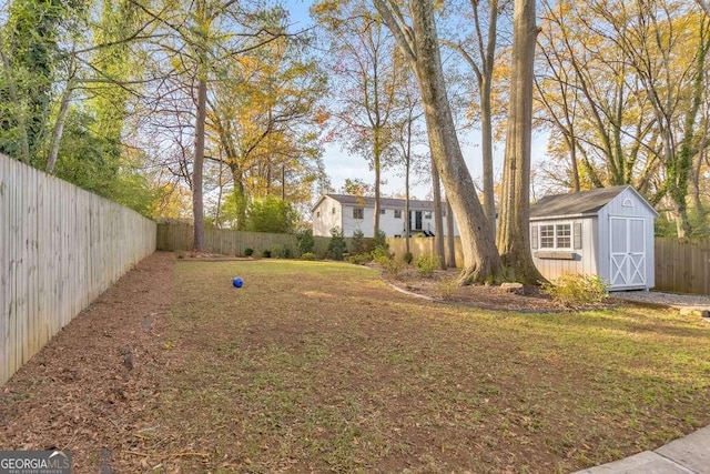 view of yard featuring an outbuilding, a fenced backyard, and a shed