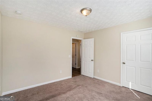 unfurnished bedroom with carpet, baseboards, and a textured ceiling