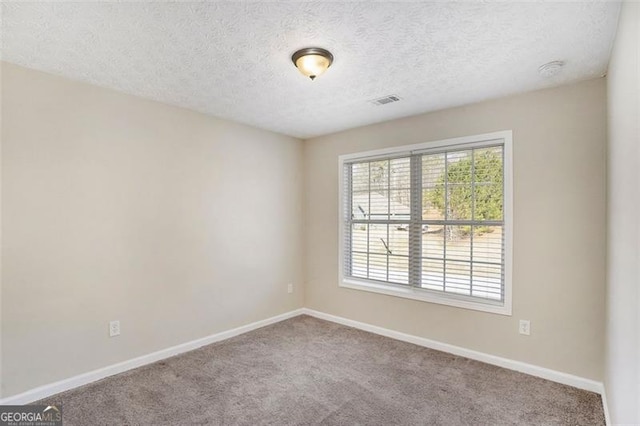 carpeted empty room with a textured ceiling, visible vents, and baseboards