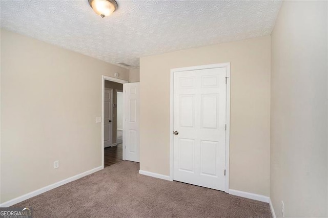 unfurnished bedroom featuring carpet, a textured ceiling, and baseboards