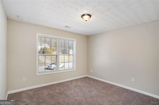 unfurnished room featuring a textured ceiling, carpet flooring, visible vents, and baseboards