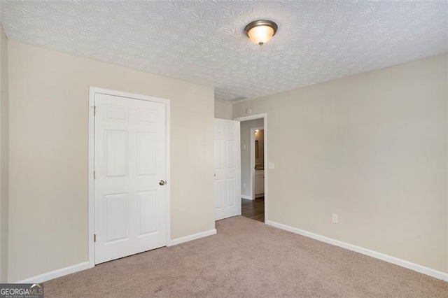 unfurnished bedroom with carpet floors, baseboards, and a textured ceiling