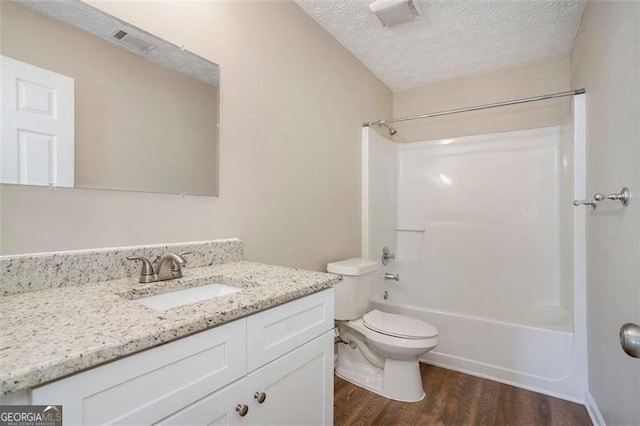 full bath with toilet, shower / tub combination, wood finished floors, a textured ceiling, and vanity