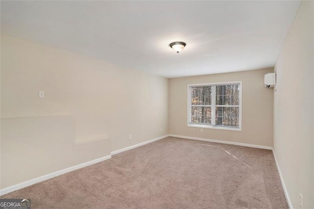 spare room featuring an AC wall unit, carpet flooring, and baseboards