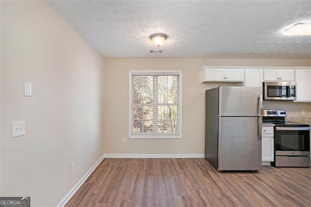 kitchen featuring baseboards, white cabinetry, appliances with stainless steel finishes, and wood finished floors