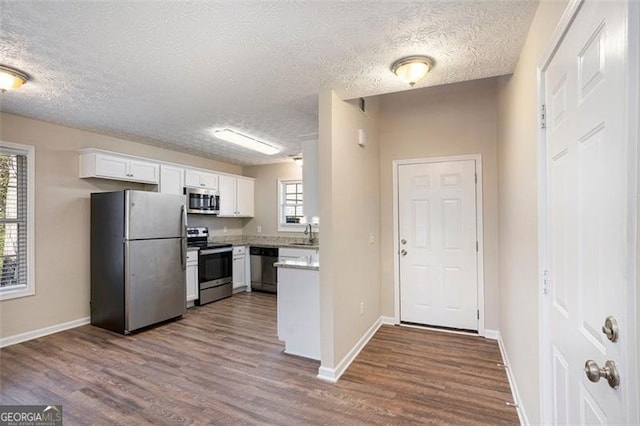 kitchen featuring white cabinets, baseboards, stainless steel appliances, and dark wood-type flooring