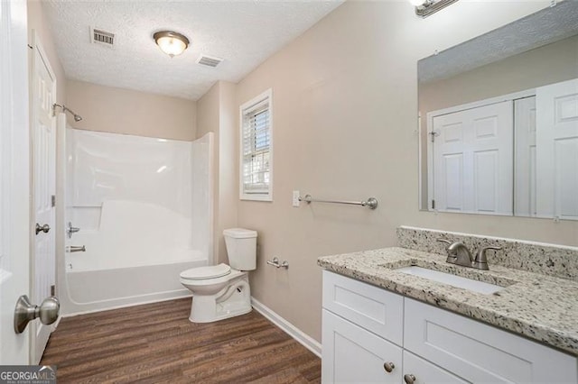 bathroom with a textured ceiling, toilet, wood finished floors, vanity, and visible vents