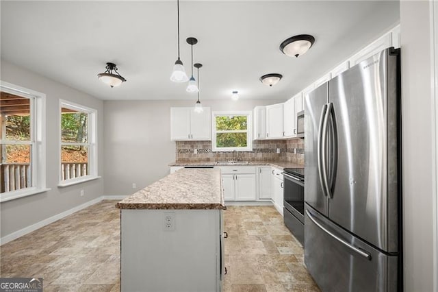 kitchen featuring white cabinets, decorative backsplash, a kitchen island, stainless steel appliances, and a sink