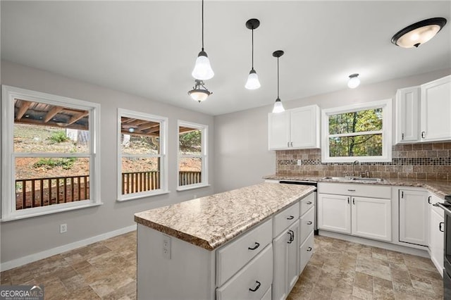 kitchen featuring decorative light fixtures, a sink, backsplash, and baseboards