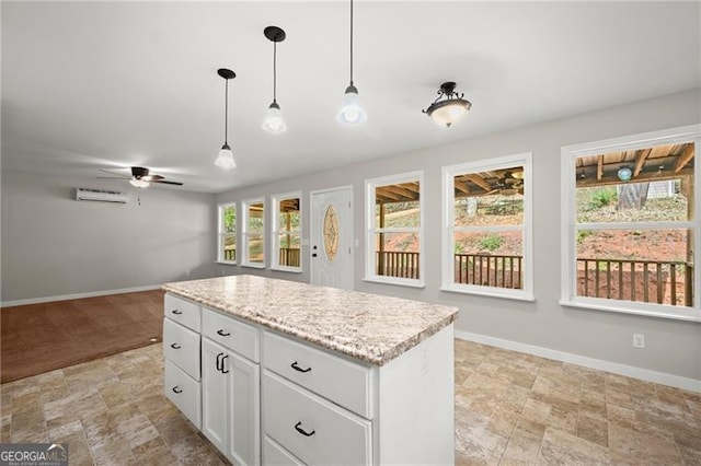 kitchen with baseboards, white cabinets, a kitchen island, decorative light fixtures, and a wall mounted AC