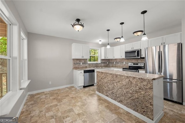 kitchen featuring backsplash, appliances with stainless steel finishes, white cabinets, light stone countertops, and baseboards