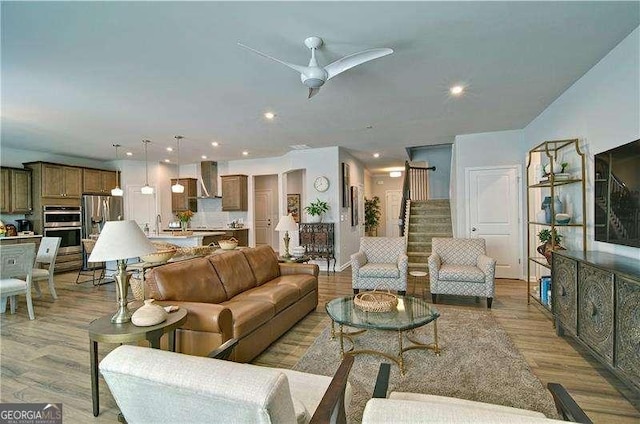 living room featuring stairs, ceiling fan, light wood-style flooring, and recessed lighting