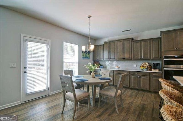 kitchen with dark wood-style floors, dark brown cabinets, stainless steel double oven, and visible vents