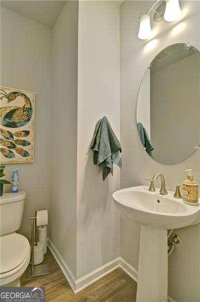 bathroom with baseboards, a sink, toilet, and wood finished floors