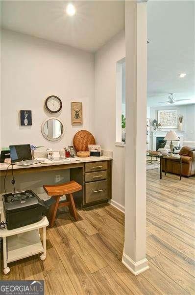 office with light wood-type flooring, a fireplace, and baseboards