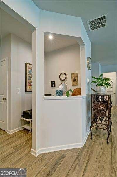 hall featuring wood finished floors, visible vents, and baseboards