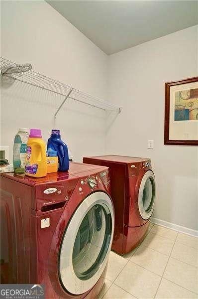 clothes washing area featuring laundry area, independent washer and dryer, baseboards, and light tile patterned floors