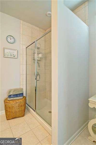 full bath with tile patterned flooring, a shower stall, and baseboards